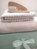 Petite Evelina Light Beige hooded towel, Beige Stripes swaddle and Little Threads wooden brush and comb displayed on sage green gift box with coordinating ribbon.