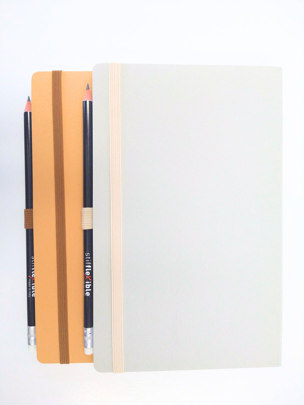 Gray and light brown Stifflexible notebooks made in Italy with attached pencils.