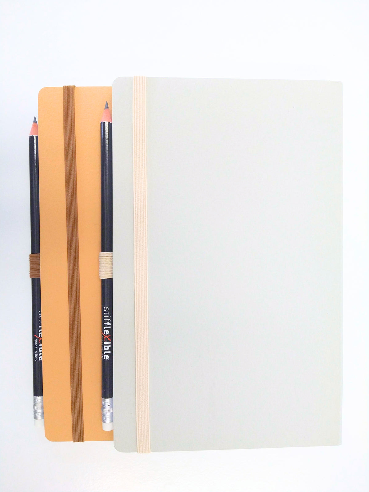 Gray and light brown Stifflexible notebooks made in Italy with attached pencils.