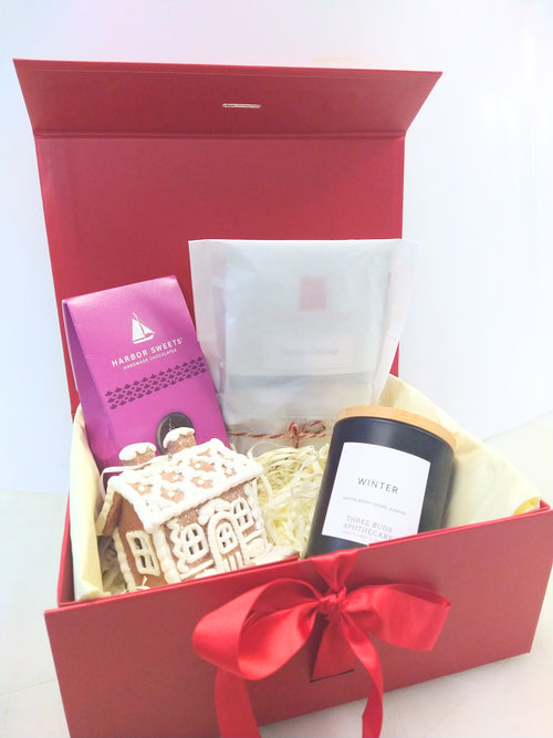 Christmas gift box with Vermont Winter candle, Harbor Sweets chocolates, assorted tea and gingerbread house decoration in a red gift box.