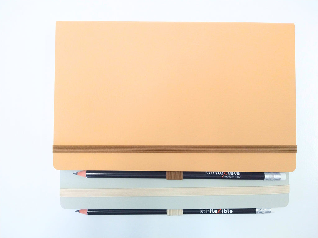 Gray and light brown Stifflexible notebooks made in Italy with attached pencils.