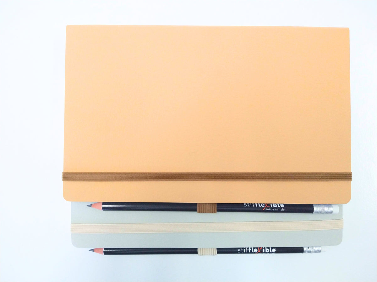 Gray and light brown Stifflexible notebooks made in Italy with attached pencils.