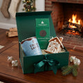 Cocoa Santé Nor'Easter hot cocoa, Harbor Sweets Marblehead Mints dark chocolates, and a decorative gingerbread house ornament displayed on coffee table.