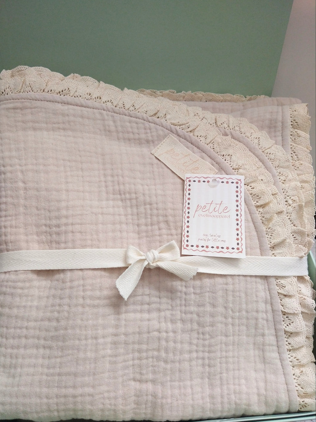 Petite Evelina light beige muslin baby blanket with lace shown inside green gift box.