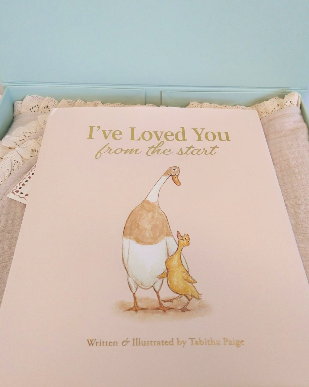 Petite Evelina beige cotton muslin baby blanket with lace trim, paired with Tabitha Paige's I've Loved You from the Start hardcover book in a sage green gift box.