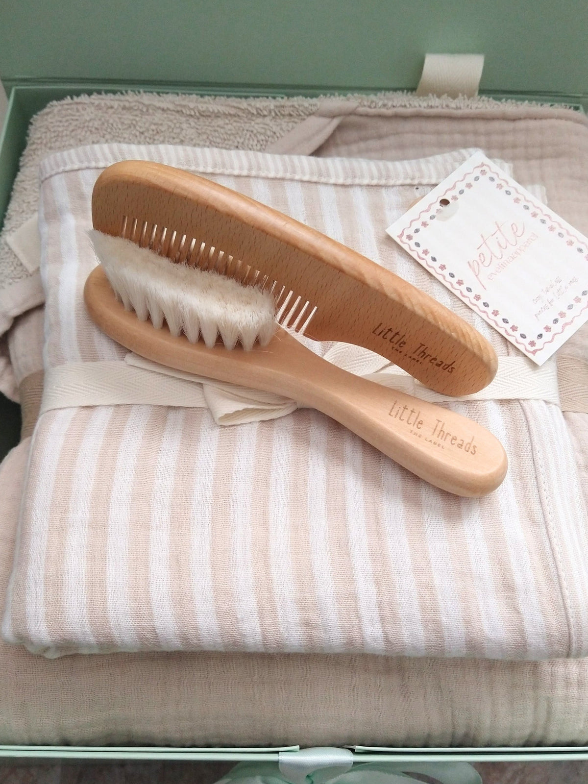 Petite Evelina Light Beige hooded towel, Beige Stripes swaddle and Little Threads wooden brush and comb shown inside sage green gift box, ready to gift.