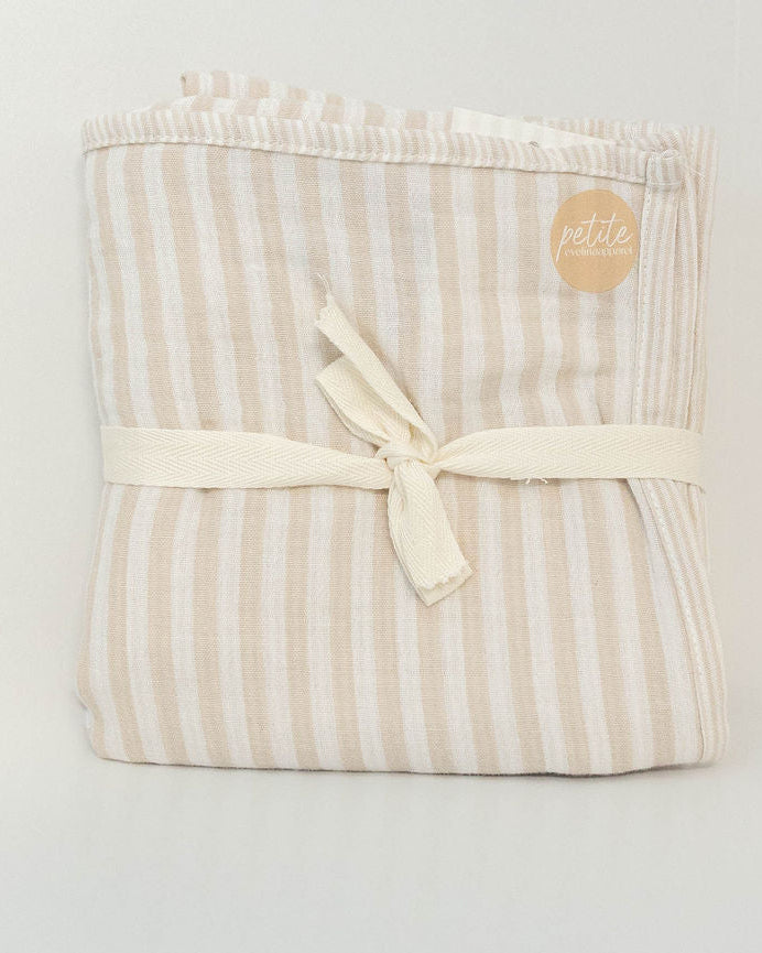 Petite Evelina beige striped muslin baby swaddle folded and tied with a cream ribbon