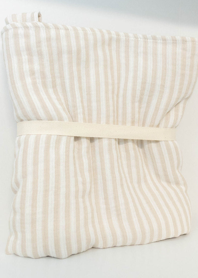 Petite Evelina beige striped baby blanket folded with cream cotton band, shown from the side