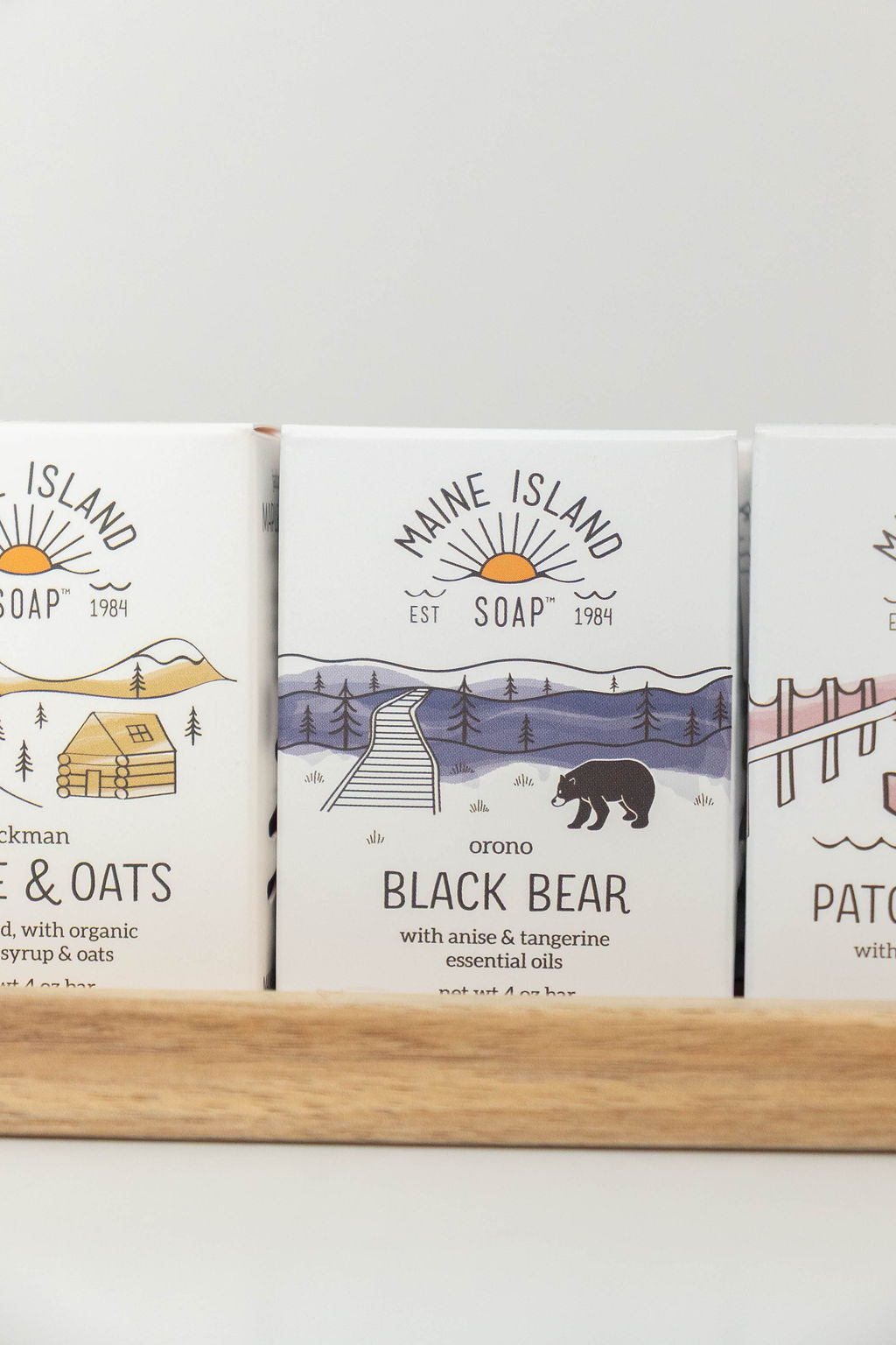Maine Island Soap Black Bear bar displayed with other scents on a wooden tray