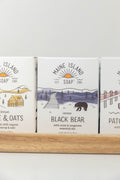 Maine Island Soap Black Bear bar displayed with other scents on a wooden tray