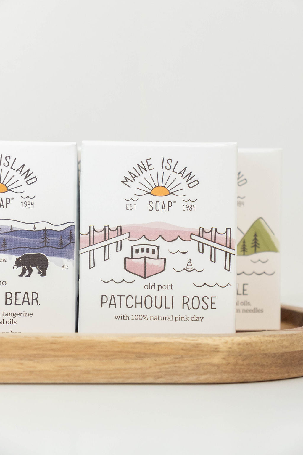 Maine Island Soap Patchouli Rose bar displayed with other scents on a wooden tray
