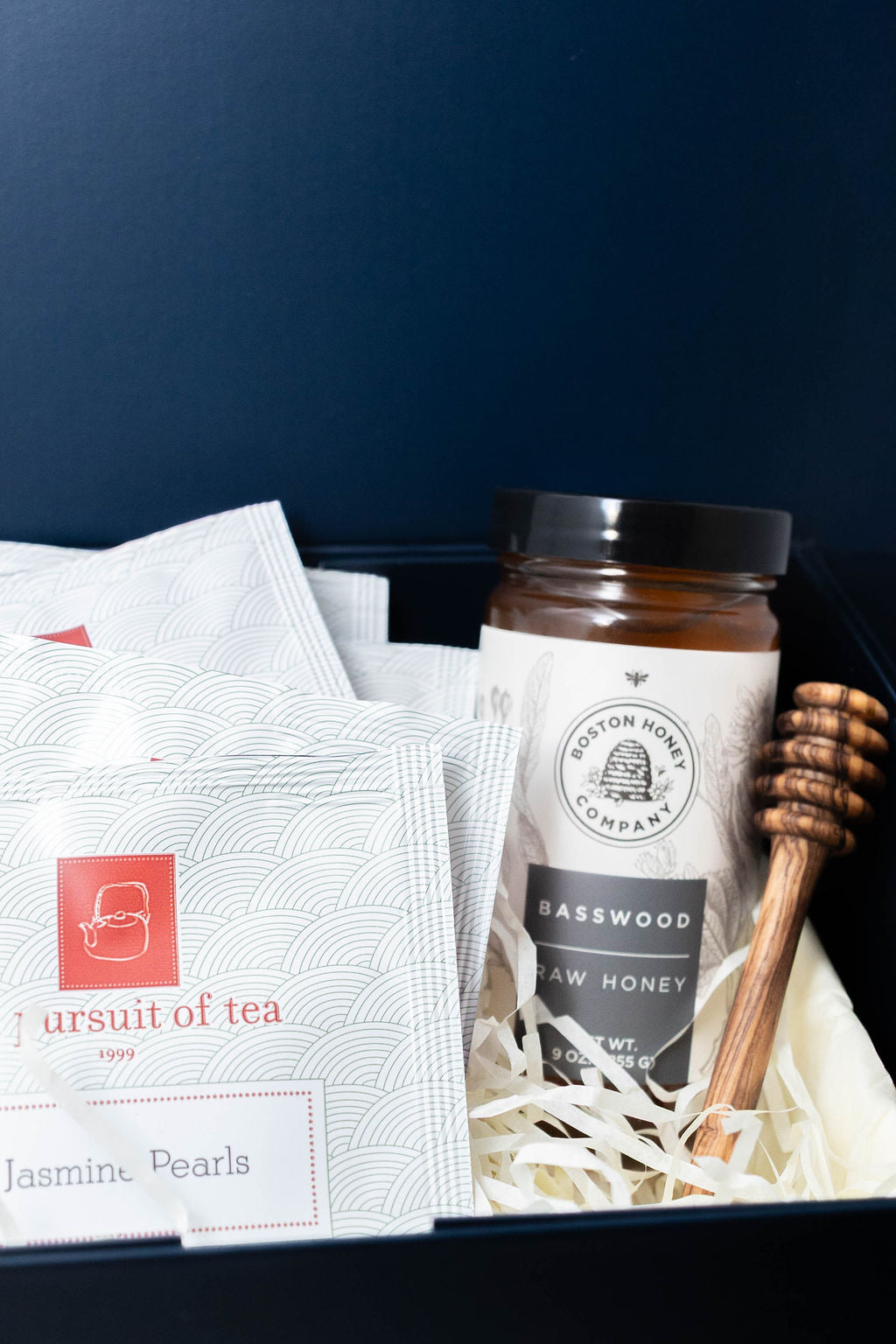 In Pursuit of Tea Jasmine Pearls sachets with Boston Honey Company basswood honey and a wooden honey dipper.