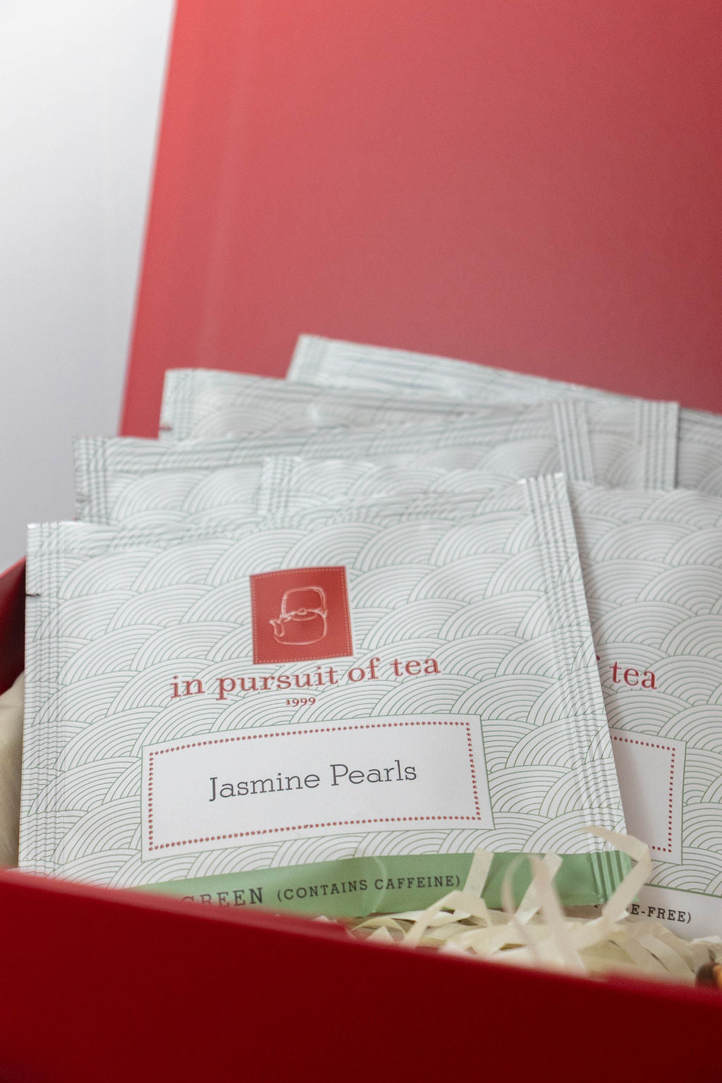 In Pursuit of Tea Jasmine Pearls tea sachets arranged in a red Solefina gift box