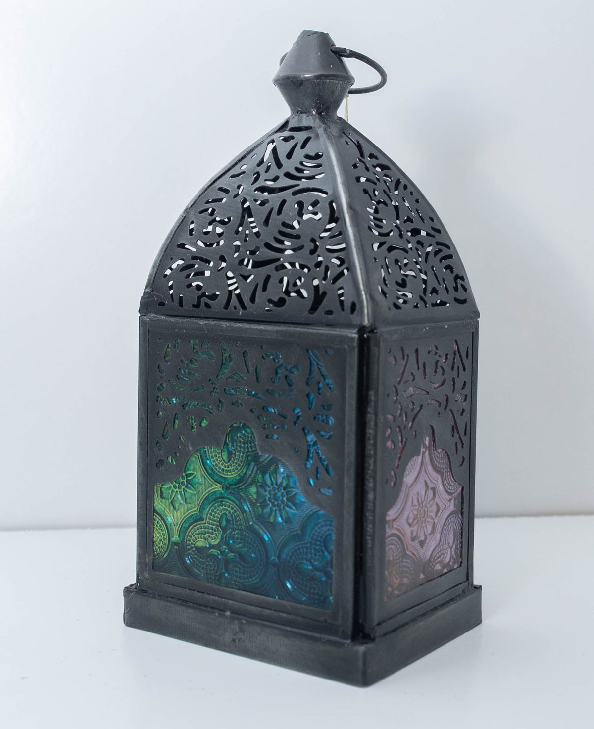 Decorative dark metal lantern with blue and green jewel-tone glass panels, individually selected in Rabat, Morocco.