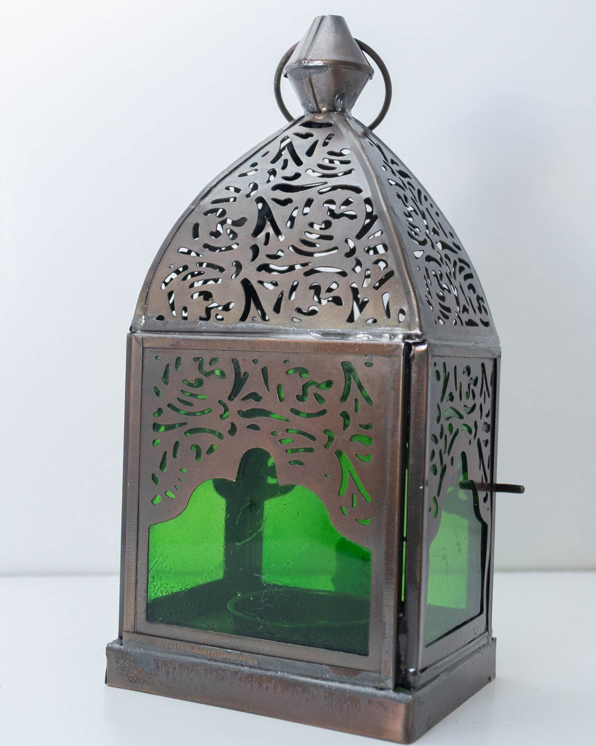 Decorative metal lantern with emerald green glass panels and pierced detailing, individually selected in Rabat, Morocco.