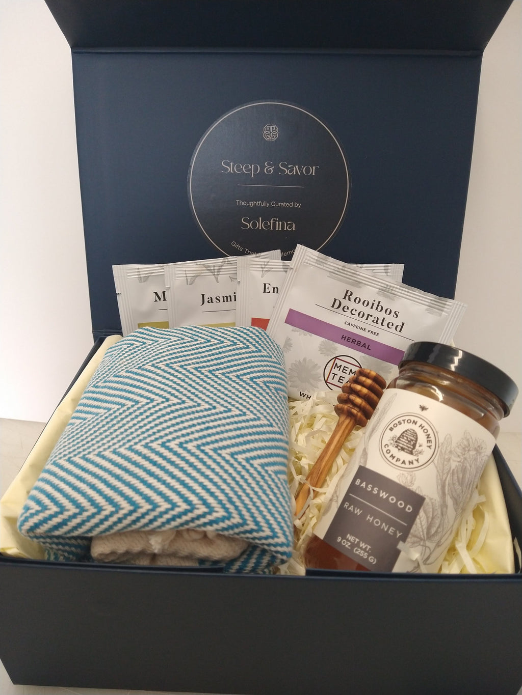 Solefina tea and honey gift box with tea sampler, basswood honey, honey dipper and blue herringbone peshtemal towel.