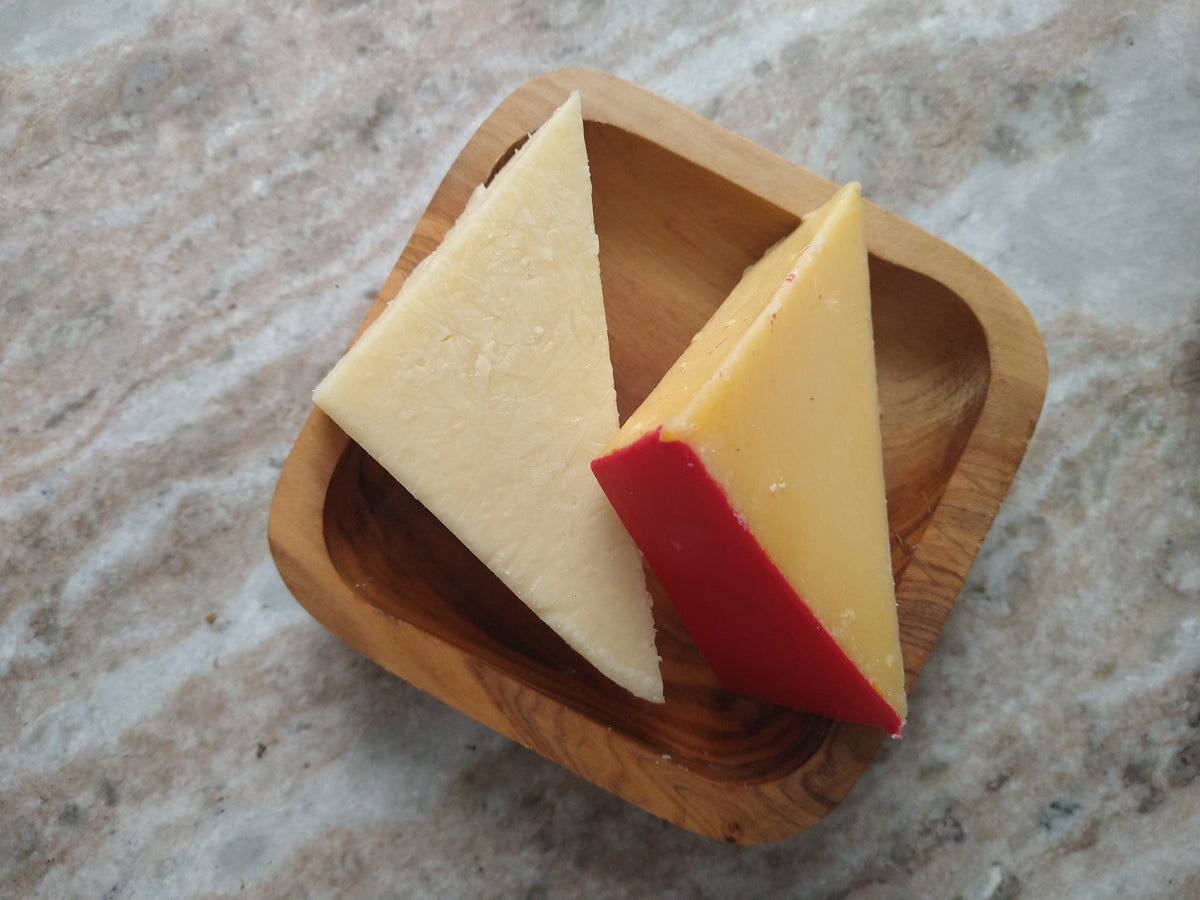 Gouda and Havarti cheese wedges arranged in a small olive wood serving dish.