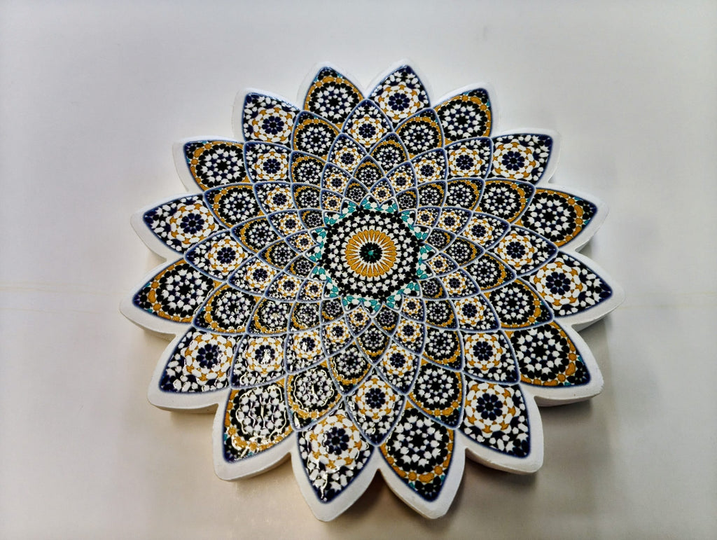 Moroccan-inspired starburst-shaped ceramic coaster featuring intricate layered geometric patterns in navy blue, lavender, gold, white and turquoise.