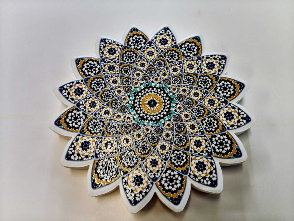 Moroccan-inspired starburst-shaped ceramic coaster featuring intricate layered geometric patterns in navy blue, lavender, gold, white and turquoise.