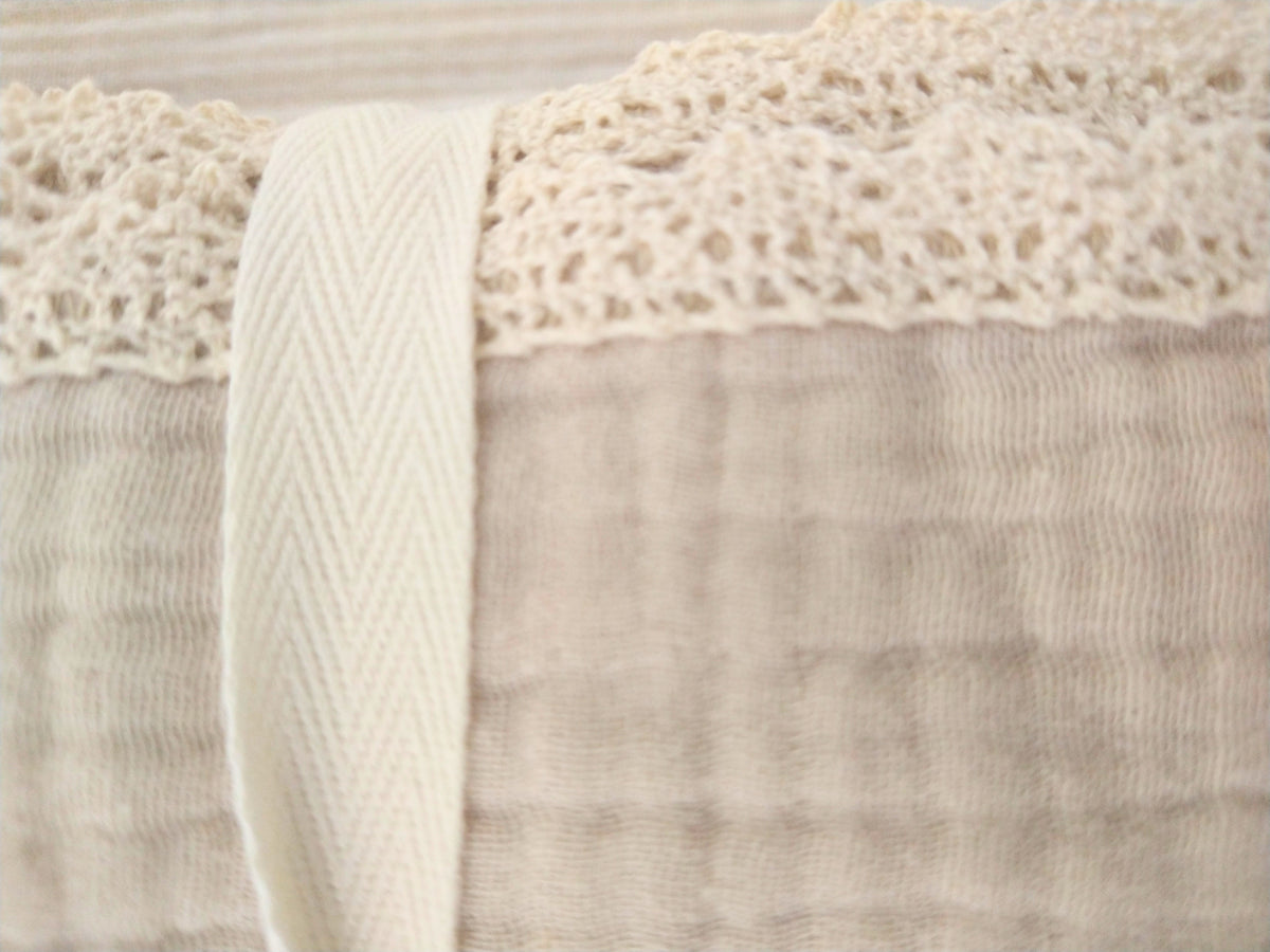 Petite Evelina light beige muslin baby swaddle showing delicate lace trim