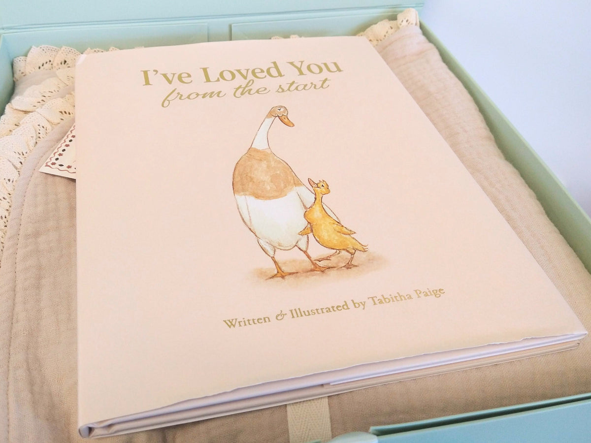 Newborn baby gift set featuring a beige lace-trimmed Petite Evelina muslin blanket and I've Loved You from the Start by Tabitha Paige, arranged in a sage green keepsake gift box.