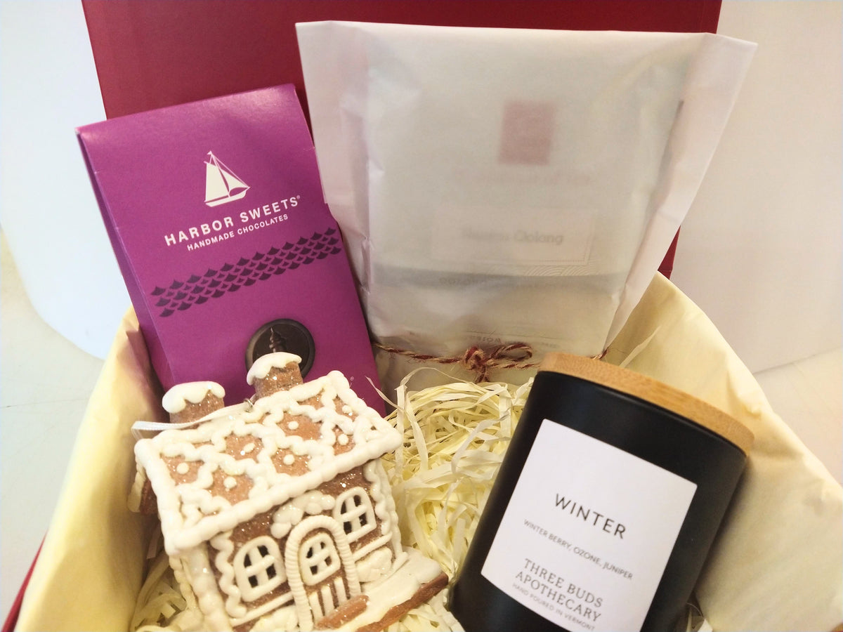 Christmas gift box with Vermont Winter candle, Harbor Sweets chocolates, assorted tea and gingerbread house decoration in a red gift box.