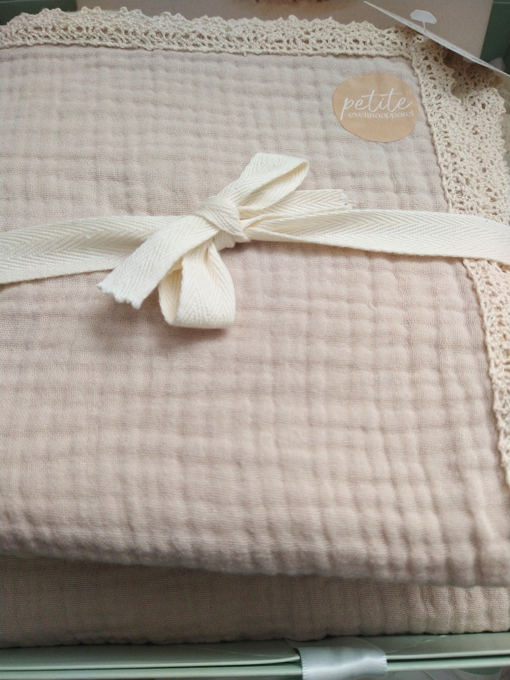 Petite Evelina light beige muslin swaddle with lace trim.