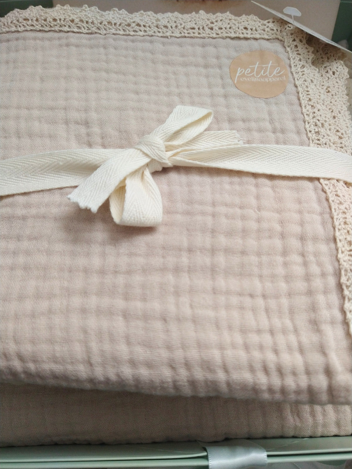 Petite Evelina light beige muslin swaddle with lace trim.